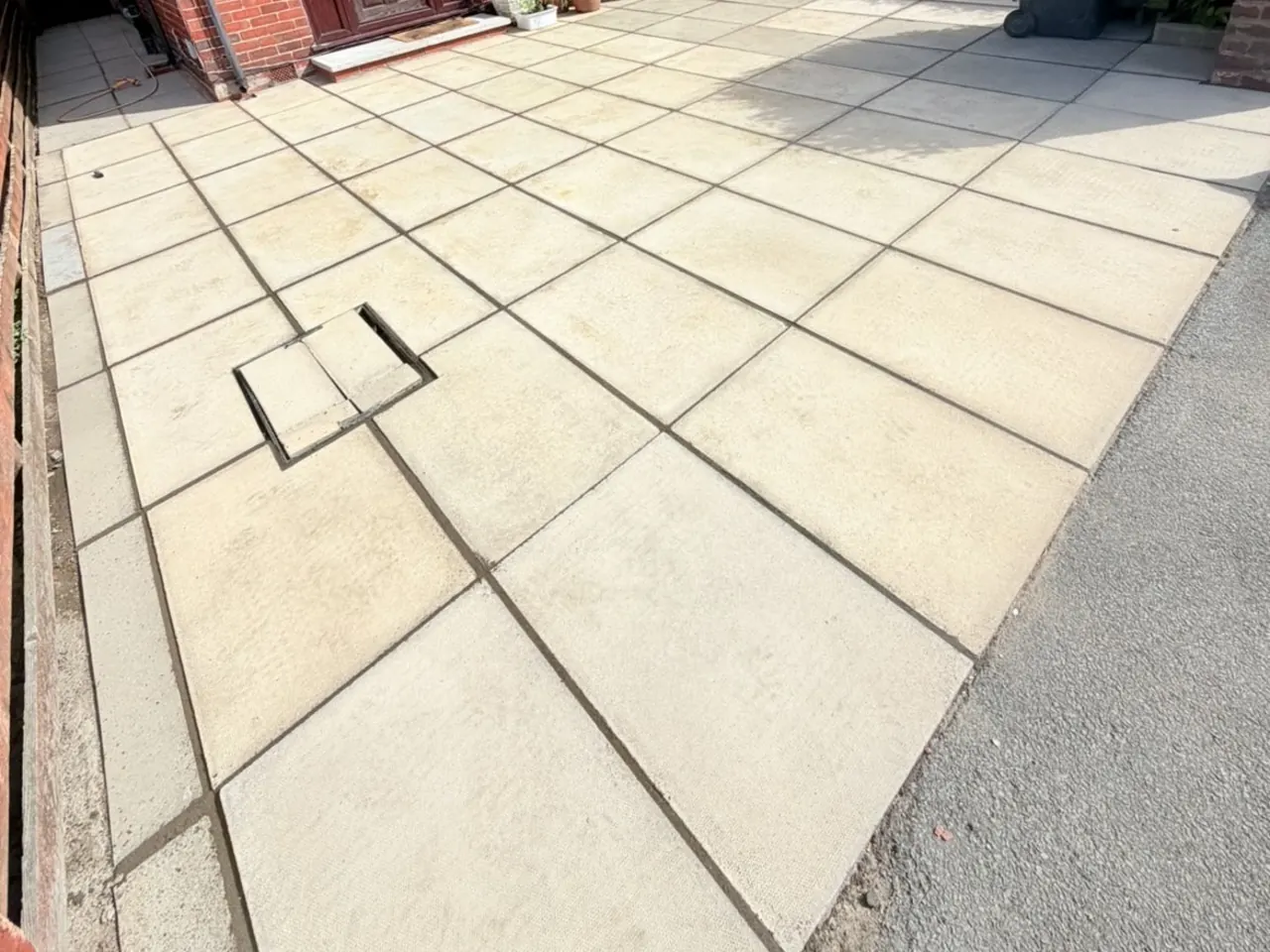 A front patio after pressure washing, the paving slabs back to a clean pale buff colour.
