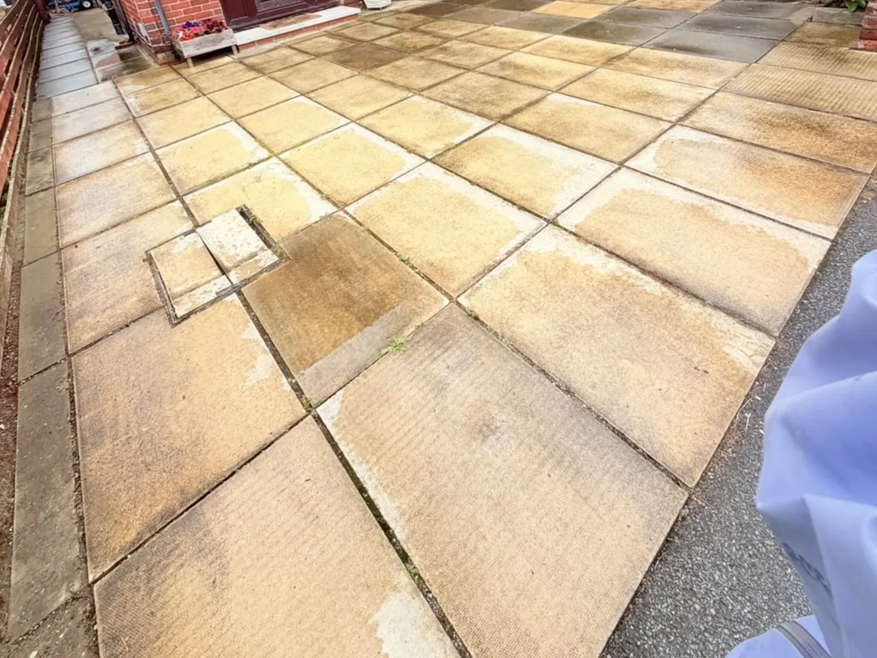 A front patio in Rhyl before cleaning, with heavy orange staining across every slab.
