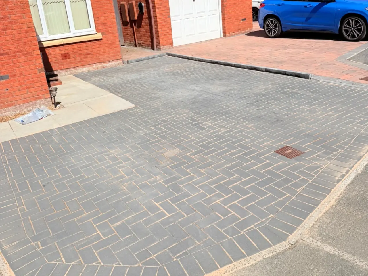 The same driveway after cleaning, the blocks back to charcoal with the buff joint lines showing again.